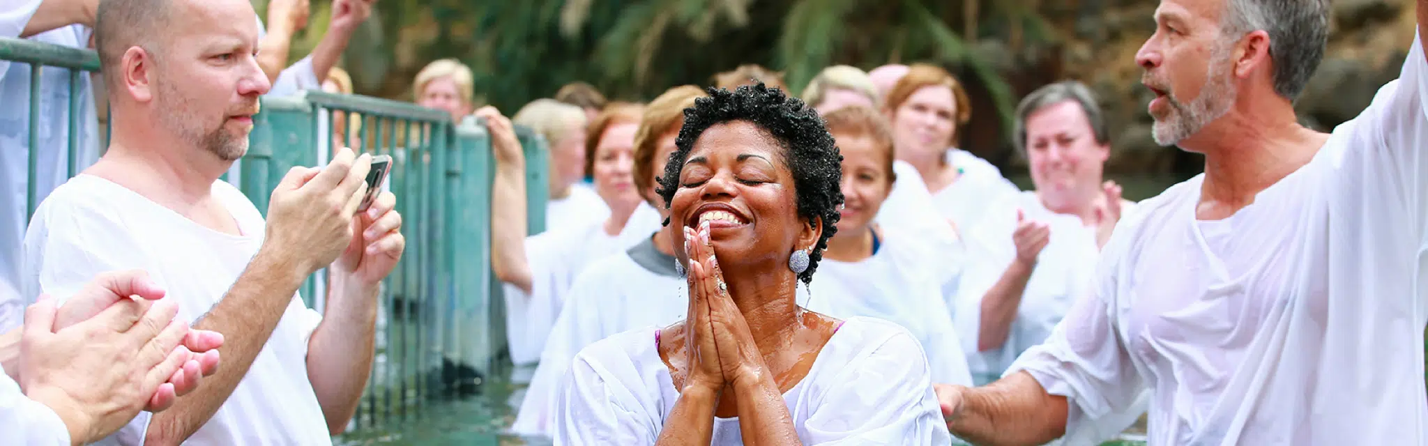 A woman expresses emotions of joy and spiritual uplifting after being baptized in the Jordan River, Sea of Galilee