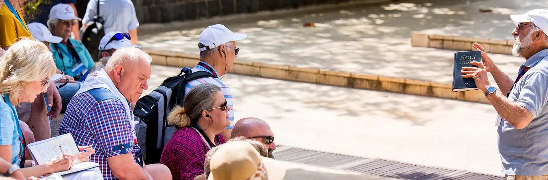America Israel Tours (AIT) tour guide teaching at the Sea of Galilee and reading from the scriptures